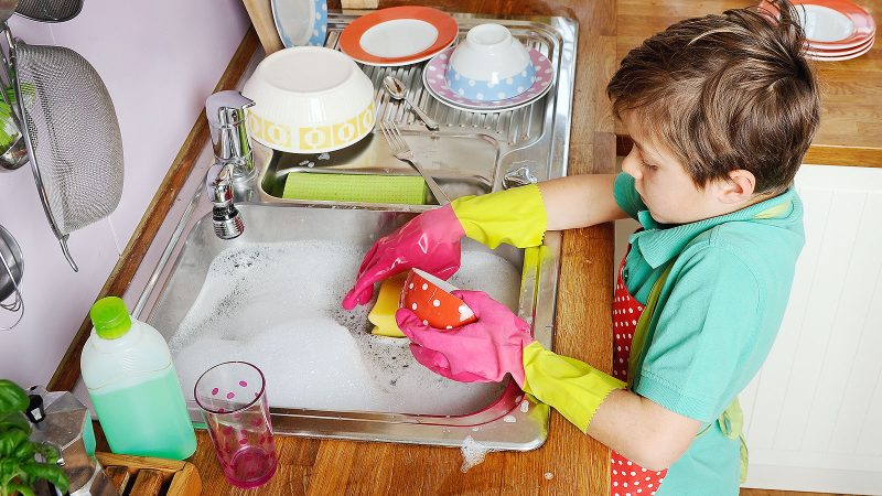 کودک در حال همکاری در شستن ظروف